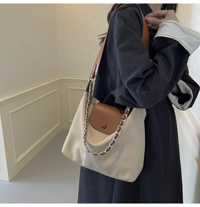 Detail of canvas tote with brown leather flap, silver chain and adjustable shoulder strap