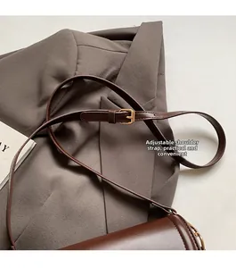 Détail de la boucle en métal doré réglable sur la bandoulière en cuir mat marron foncé