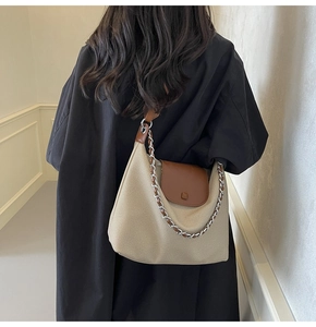 Detail of canvas tote bag with brown leather trim and metal chain decoration