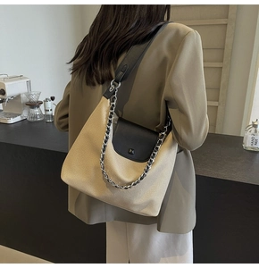 Detail of light brown canvas tote with black leather flap and silver chain strap