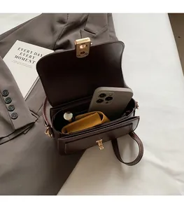 Vue intérieure d'un sac bandoulière marron montrant le rangement du téléphone et du portefeuille