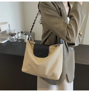 Model wearing a chic beige canvas tote bag with black leather flap and chain strap
