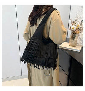 Rückansicht einer schwarzen Hobo-Schultertasche mit dichten Fransen an einem Model
