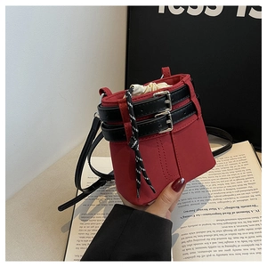 Détail du sac seau rouge avec fermeture à cordon et ceintures décoratives en cuir noir