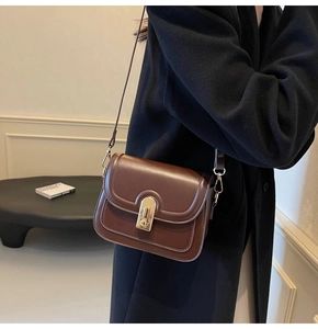 Détail d'un sac bandoulière en cuir marron foncé avec fermoir rotatif doré élégant