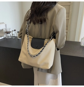 Detail of woven tote bag featuring a black leather flap and patterned shoulder strap