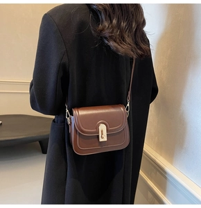 Vue détaillée du sac bandoulière en cuir marron avec fermoir rotatif doré vintage