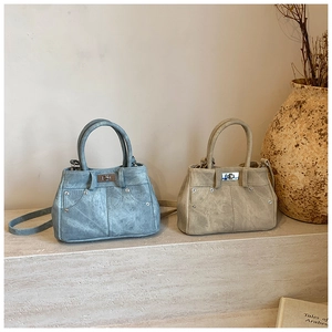 Detail view of retro leather handbags in blue and beige with metal twist locks and studs