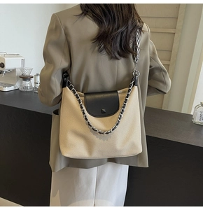 Detail of beige canvas tote with black leather trim, metallic studs and geometric strap