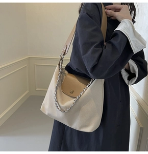 Detail of canvas tote bag with brown leather straps and silver chain decoration