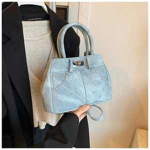 Close-up of light blue denim handbag with pocket stitching and metal rivet details