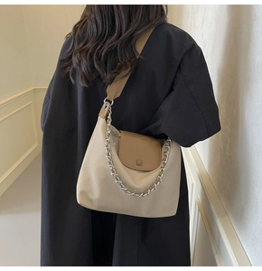Detail of canvas hobo bag with brown leather flap and silver chain on model