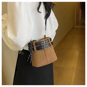 Détail du sac seau en cuir mat marron avec foulard décoratif et boucles noires