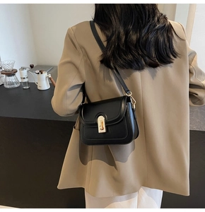 Sac bandoulière classique en cuir noir avec boucle dorée porté par un mannequin