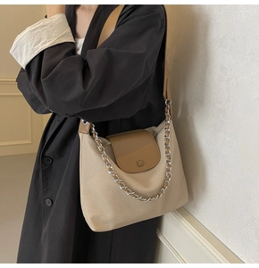 Detail of canvas tote bag with brown leather trim and silver metal chain decoration