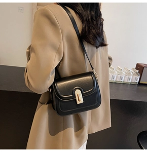 Détail d'un sac bandoulière chic en cuir noir doté d'un fermoir doré rectangulaire
