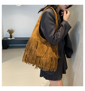 Detail einer braunen Wildleder-Hobo-Tasche mit langen Fransen und breitem Gurt