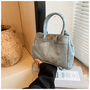 Detail of light blue denim tote bag with metal twist lock and decorative stitching