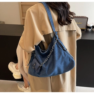 Detail of dark denim tote bag with silver chain accessory and matching mini pouch