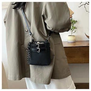 Détail d'un mini sac seau noir avec boucles argentées et une pochette intérieure à cordon