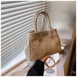 Detailed shot of khaki suede texture with metallic studs and a turn-lock on the tote bag