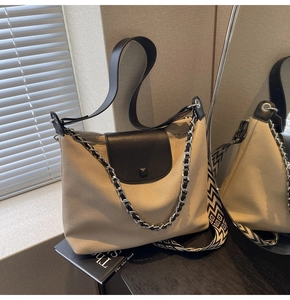 Detail of canvas tote bag with black leather flap, chain strap and geometric strap