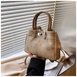 Detail of vintage beige mini handbag with denim pocket stitching and metal turn-lock