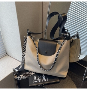 Detail view of a beige canvas and black leather tote bag with a patterned wide strap