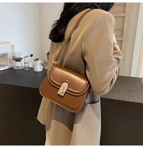 Vue détaillée du sac bandoulière en cuir marron avec boucle dorée et coutures fines
