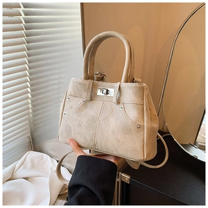 Detail of beige textured handbag featuring creative pocket design and silver metal lock