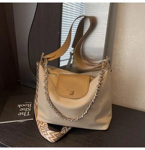 Detail of canvas tote bag featuring chain link handle and wide jacquard woven strap