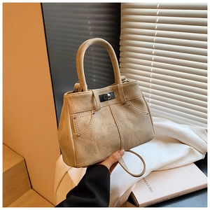 Detail view of khaki handbag with denim pocket design, metal studs and smooth swivel lock