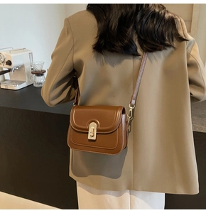 Détail d'un sac à bandoulière en cuir marron avec une boucle en métal doré classique
