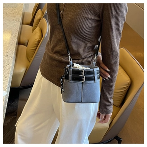 Détail du sac seau en denim bleu avec lanières de ceinture noires et fermeture à cordon