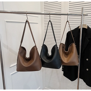 Detailed view of three pebbled leather bucket bags in black, dark brown, and tan colors