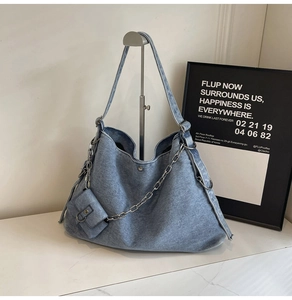 Detail of light blue denim tote bag with silver chain and matching mini pouch