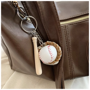 Detail of baseball charm with bat, ball, and glove on brown leather tote bag