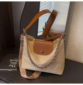 Detail of woven tote bag with brown leather flap and bohemian geometric wide shoulder strap