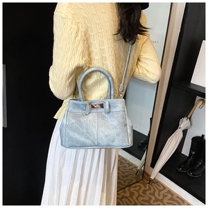 Detail of light blue denim tote bag worn as a crossbody bag by a female model