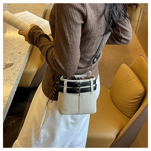Détail du sac seau en cuir gris mat avec lanières à boucles noires et cordon de serrage