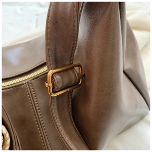Detailed close-up of brown pebbled leather texture with stitching and brass hardware
