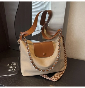 Detail of canvas tote bag featuring brown leather trim and patterned wide shoulder strap