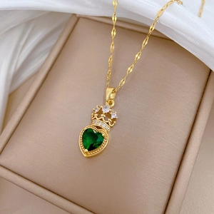 Macro shot of gold crown necklace featuring heart-shaped emerald zircon in a beige jewelry box