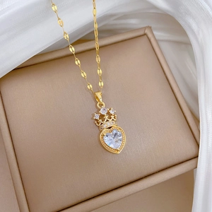 Detailed macro of a gold crown heart necklace featuring a large cubic zirconia stone