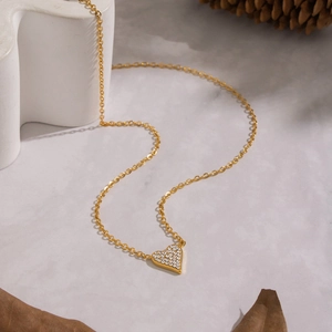 Macro shot of gold heart pendant with pavé white zircon stones on stone background