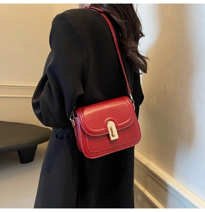 Sac bandoulière carré rouge vintage avec fermoir doré porté par un mannequin chic