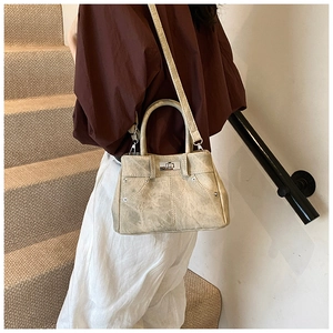 Detail of beige vintage crossbody bag with silver twist lock and rivet accents