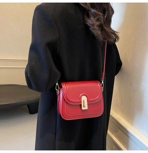 Détail du sac bandoulière en cuir rouge avec boucle dorée et coutures fines