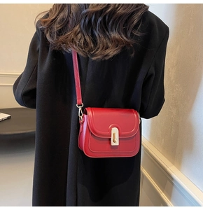Détail du sac bandoulière carré rouge avec fermoir doré sur mannequin en noir