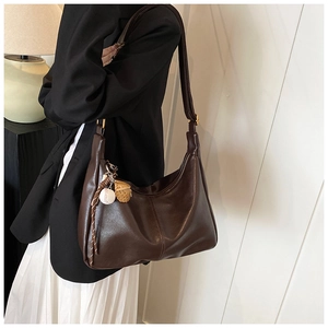 Detail of dark brown hobo bag with unique baseball and glove charms for a stylish look